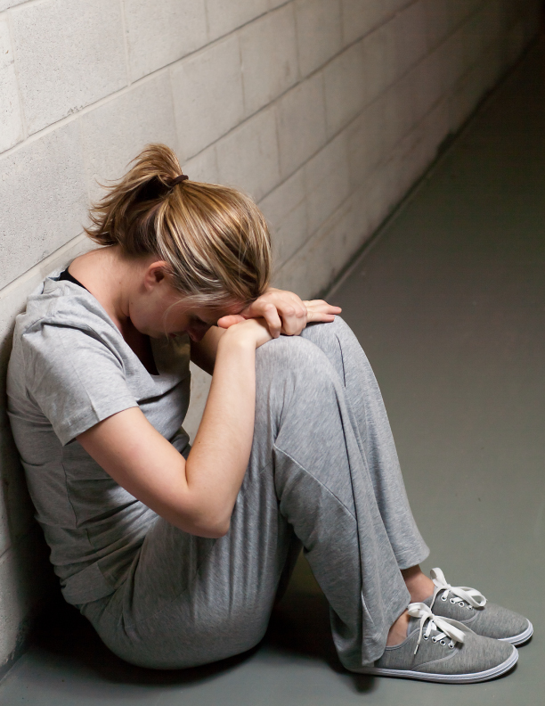 A student sits on the group with their head against their knees, crying