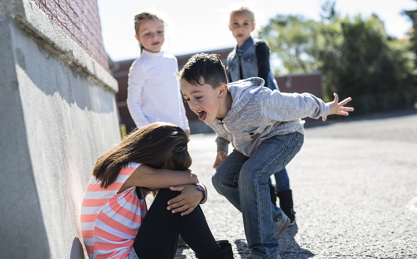 boy bullying girl as students look on